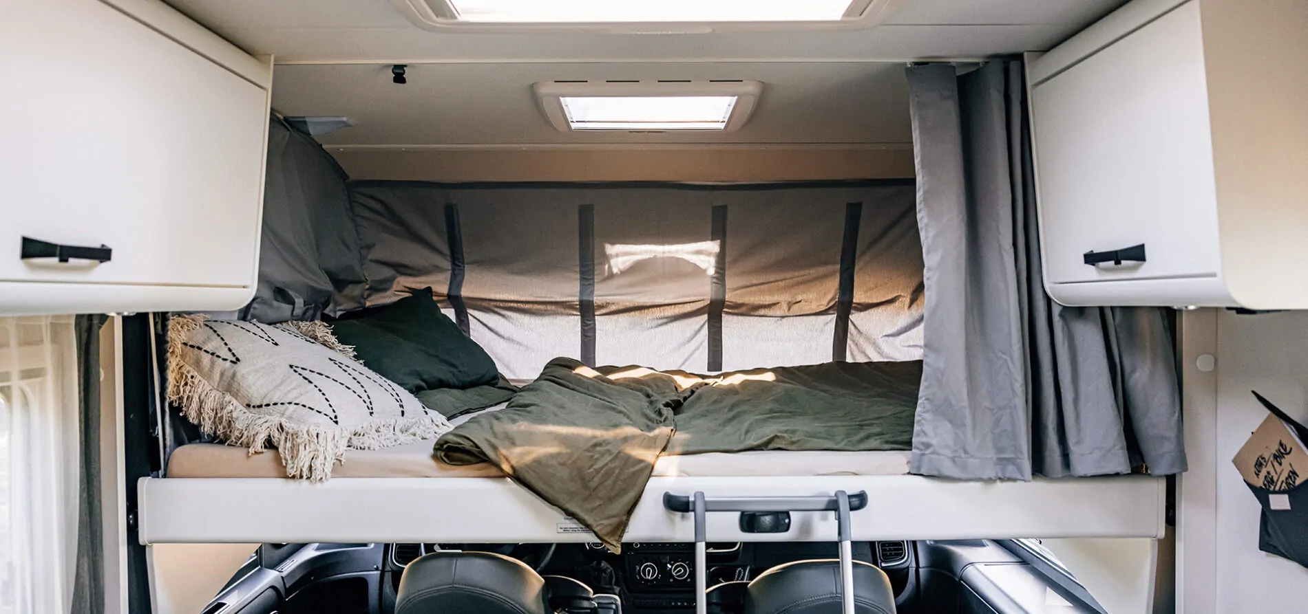 Schlafbereich in einem Wohnmobil mit Bett und Kissen.