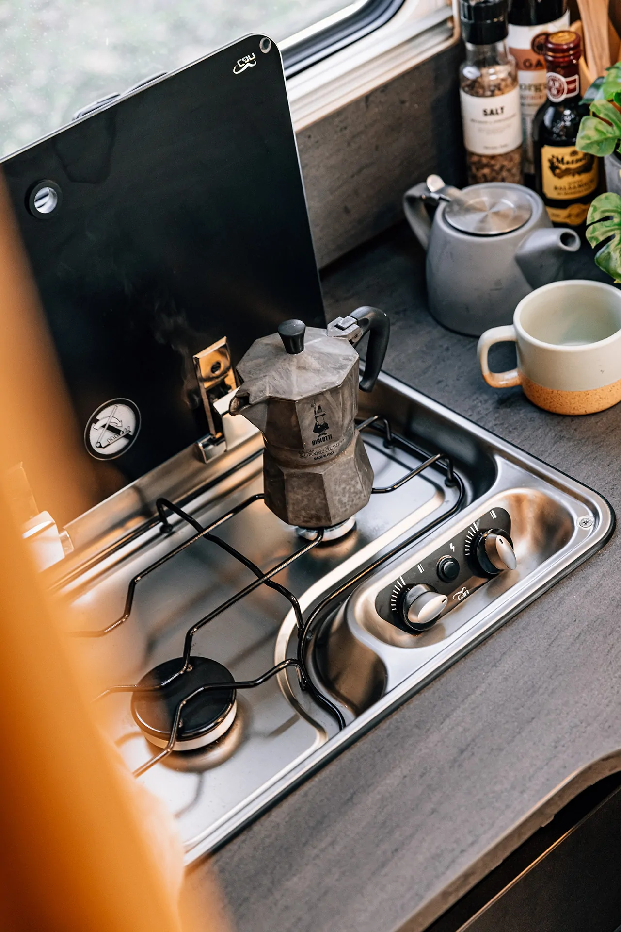 Eine Mokkakanne steht auf einem Gasherd in einer Wohnmobilküche.