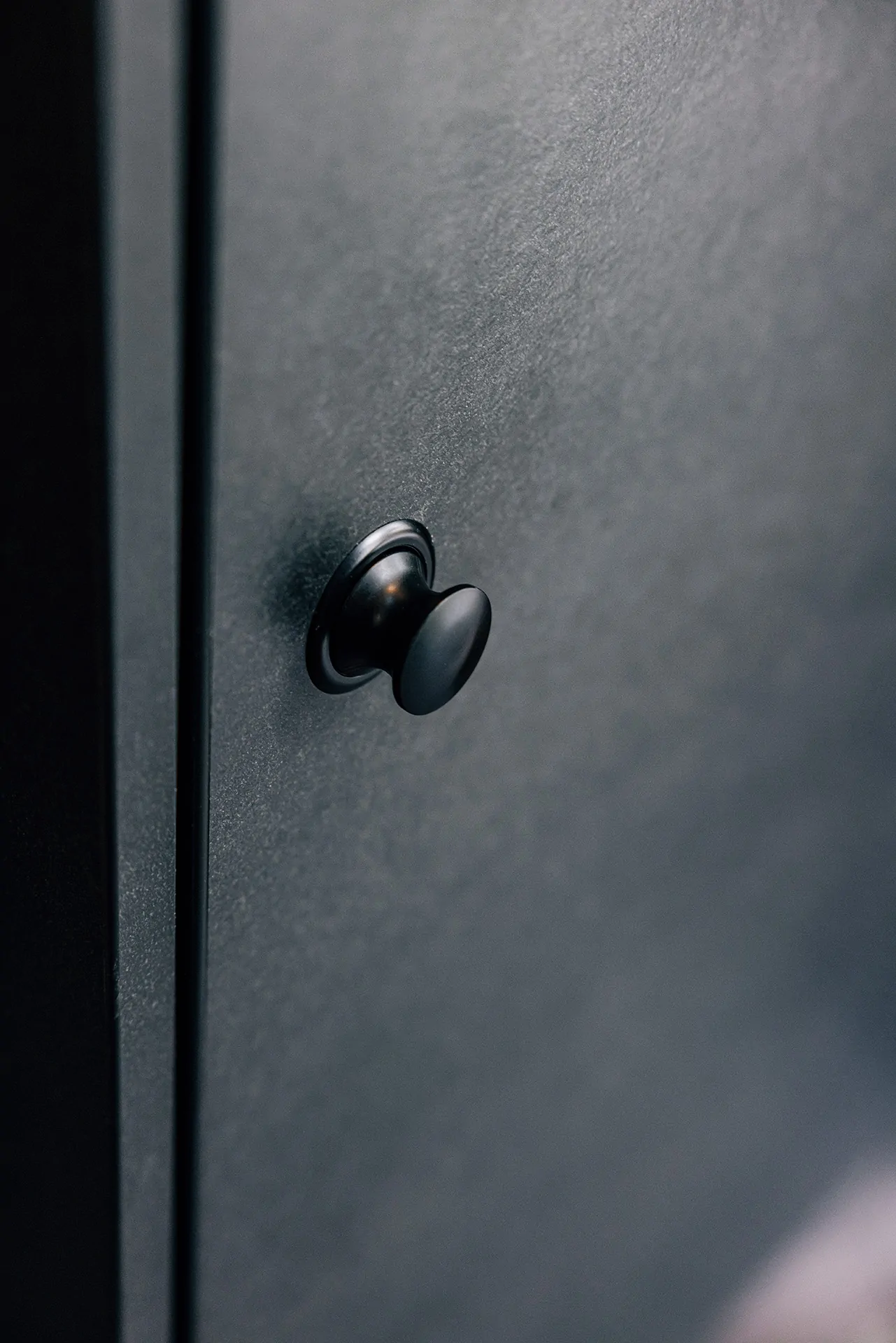 Schwarzer Knopf an einer dunklen Oberfläche.