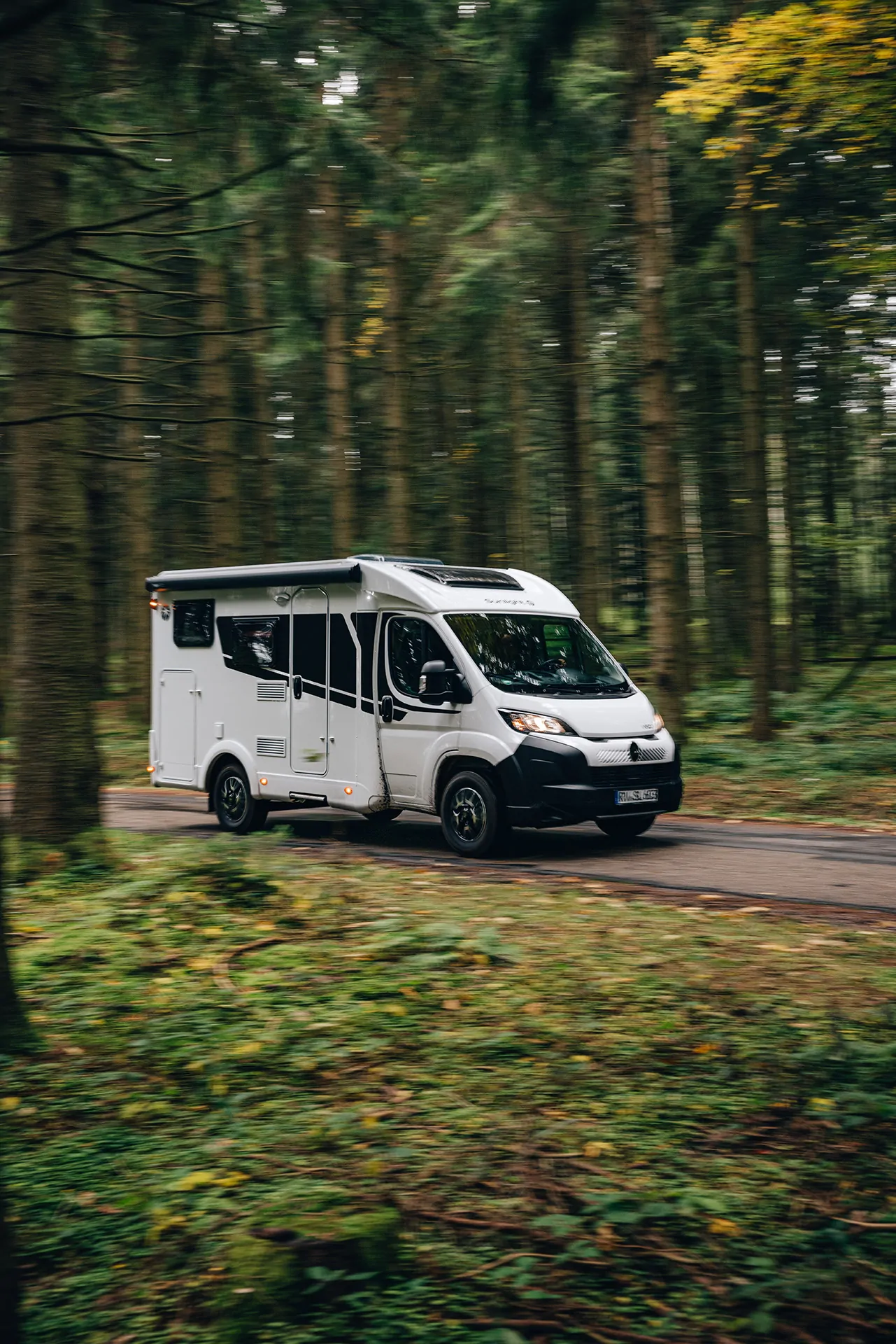 Wohnmobil der Marke Sunlight fährt durch einen Wald.