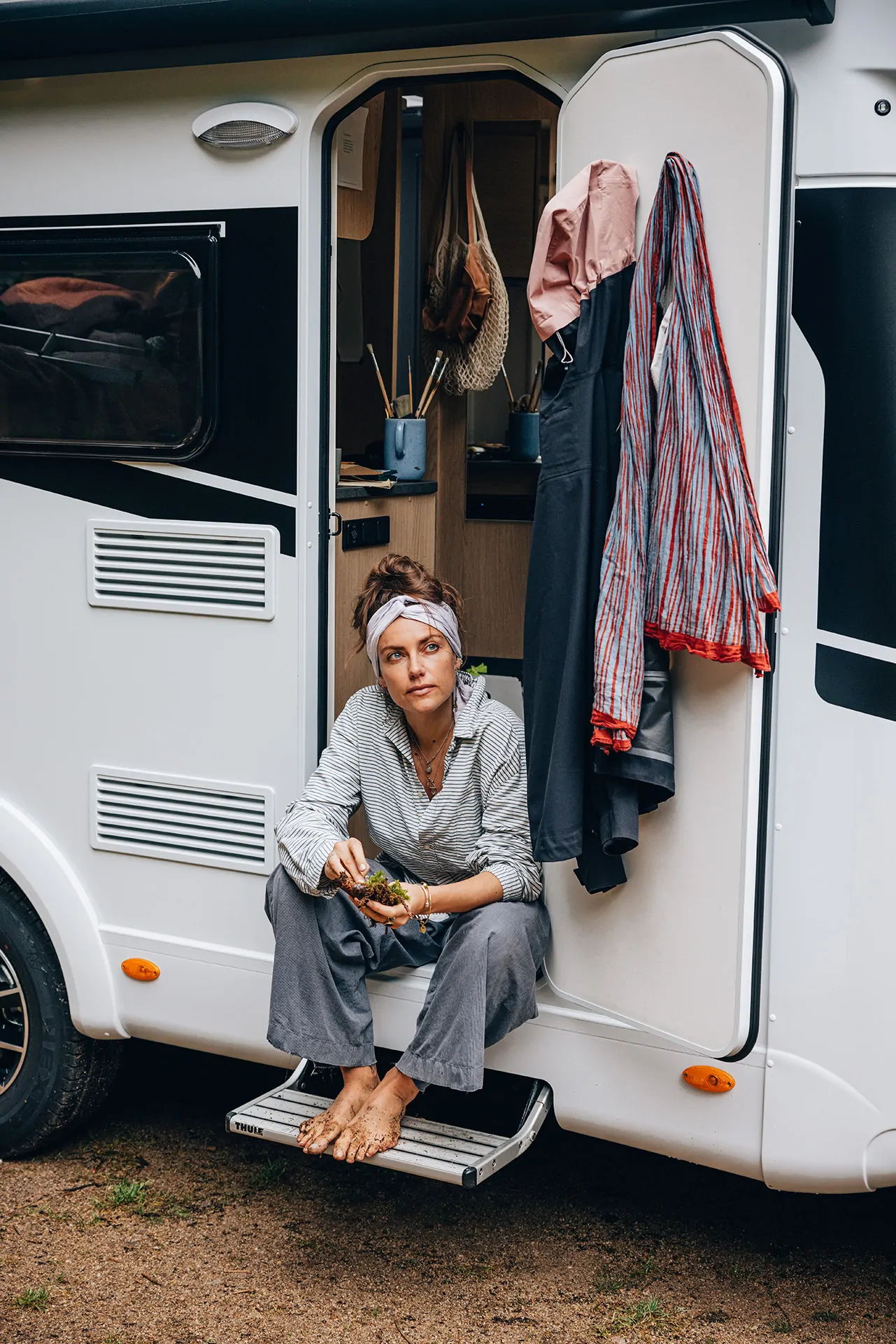 Frau sitzt barfuß auf der Stufe eines Sunlight Vans.