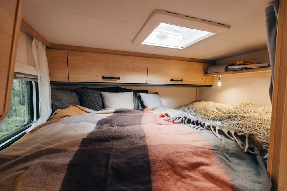 Innenraum eines Sunlight Vans mit gemütlichem Bett und Dachfenster.