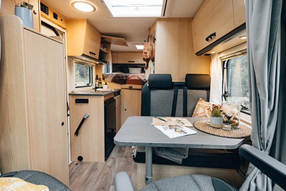 Innenansicht eines Sunlight Vans mit Küche, Esstisch und Sitzbereich.