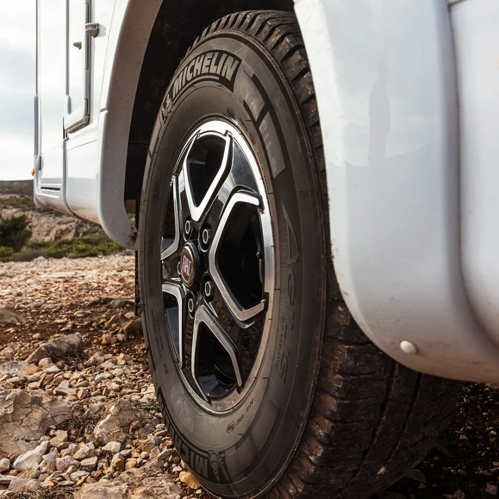 Nahaufnahme eines Wohnmobilreifens der Marke Michelin auf einem steinigen Untergrund.