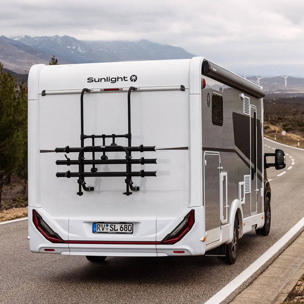 Ein teilintegriertes Wohnmobil der Marke Sunlight fährt auf einer Landstraße.