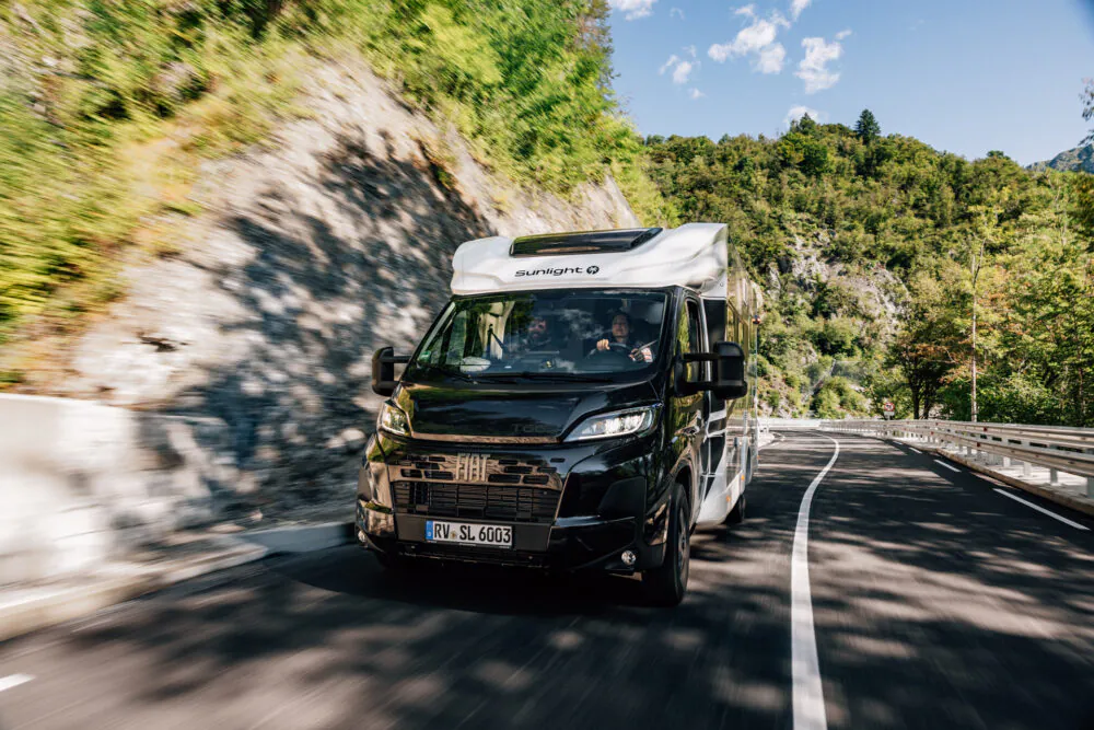 Ein teilintegriertes Sunlight Wohnmobil fährt auf einer kurvigen Bergstraße.
