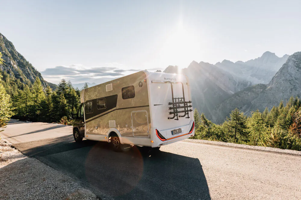 Teilintegriertes Wohnmobil auf einer Bergstraße bei Sonnenuntergang.