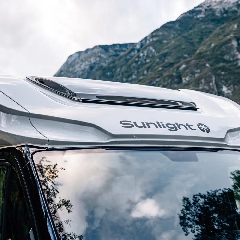 Teilintegriertes Wohnmobil der Marke Sunlight vor einer Berglandschaft.