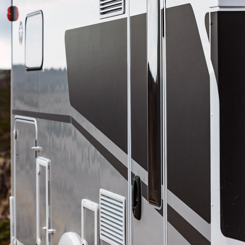 Seitenansicht eines teilintegrierten Adventure-Wohnmobils mit grauen und schwarzen Streifen.