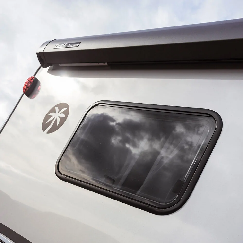 Seitenansicht eines teilintegrierten Wohnmobils mit Fenster und Palme-Logo.