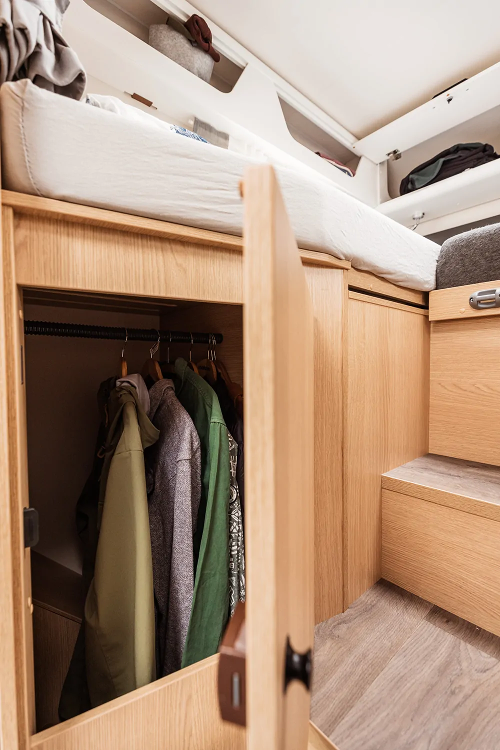 Offener Kleiderschrank in einem teilintegrierten Wohnmobil mit hängenden Jacken.