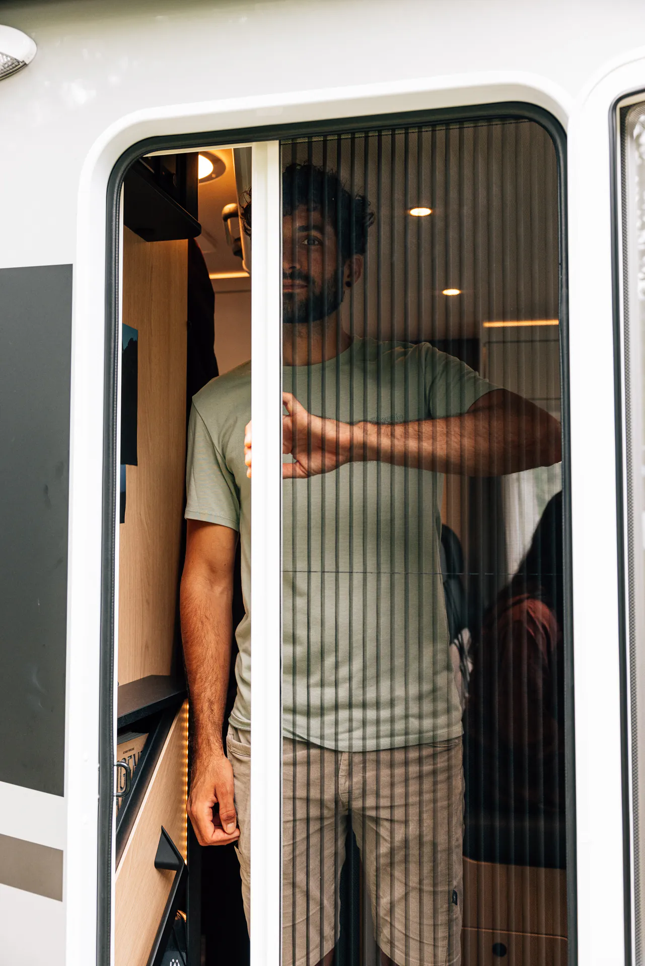 Eine Person steht in einem Wohnmobil und öffnet eine Schiebetür.