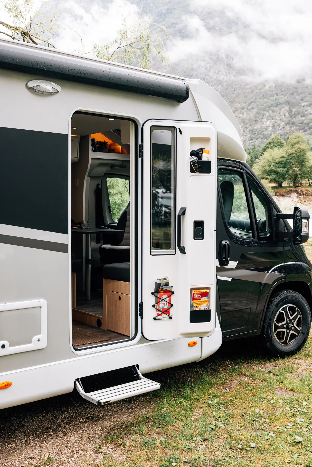 Teilintegriertes Wohnmobil mit geöffneter Tür und Blick ins Innere.