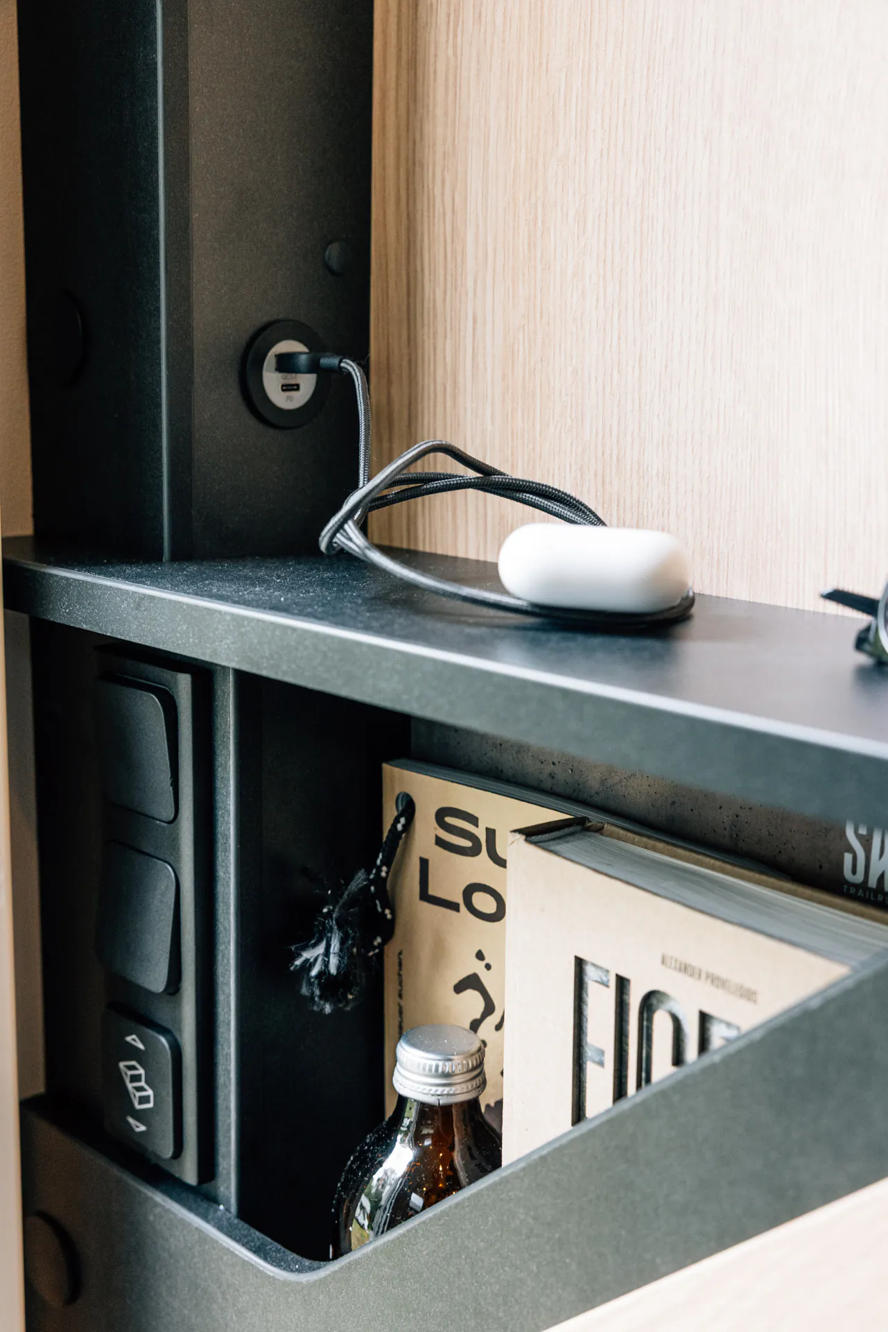 Regal mit USB-Anschluss, Ladekabel, Büchern und einer Flasche.