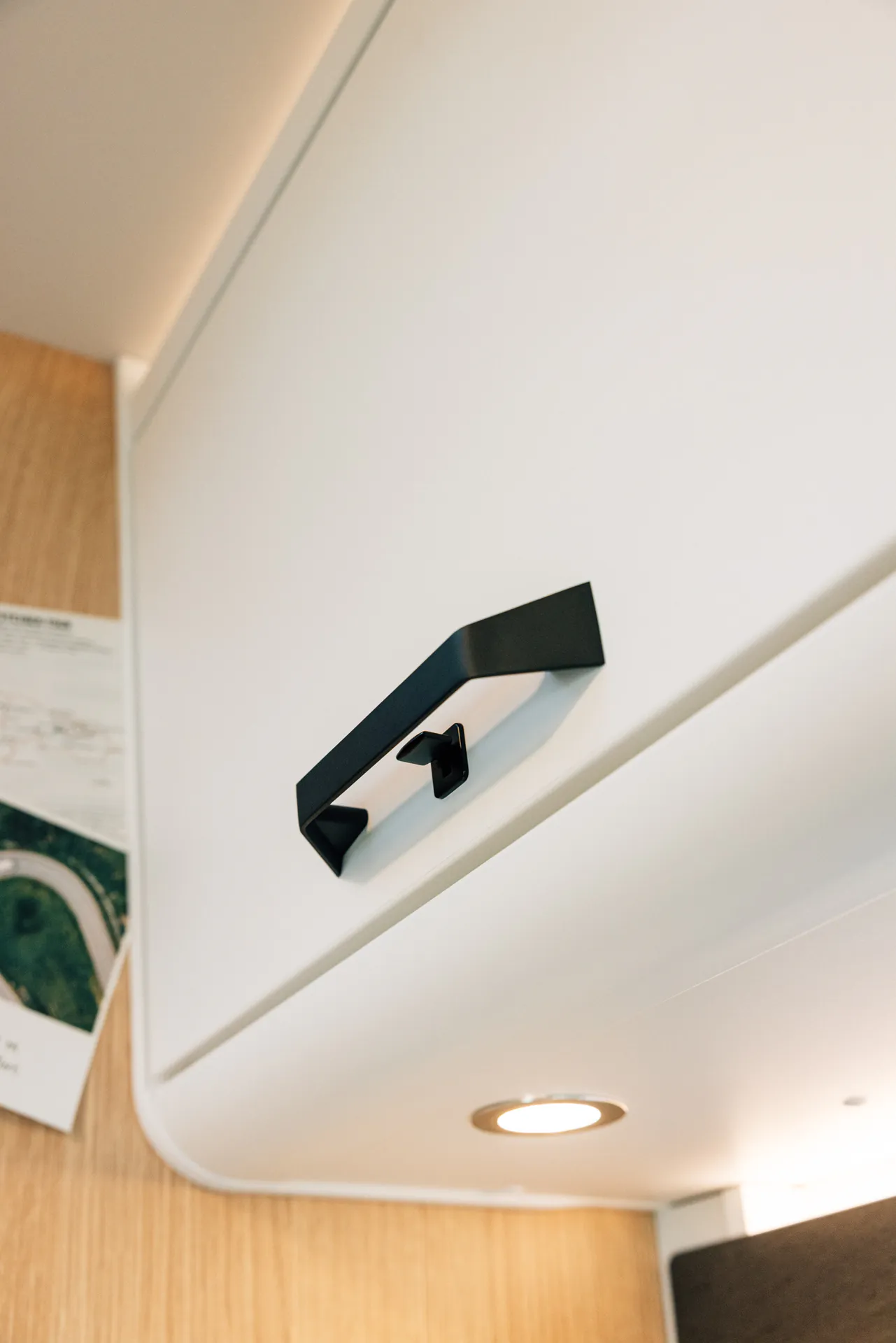 Weiße Schranktür mit schwarzem Griff in einem Wohnmobil.