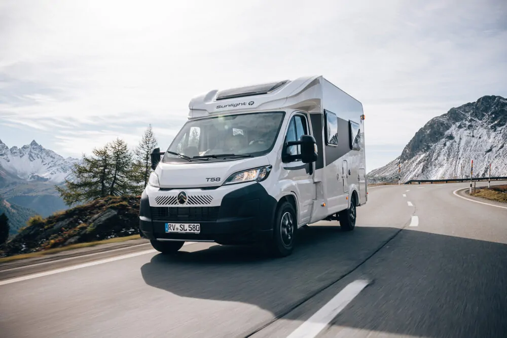 Ein weißer Sunlight T58 Teilintegrierter Camper fährt auf einer kurvigen Bergstraße.