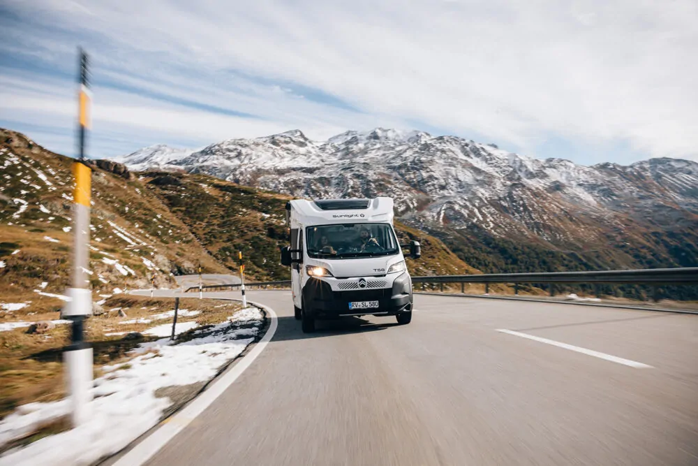 Ein teilintegriertes Wohnmobil fährt auf einer kurvigen Bergstraße.
