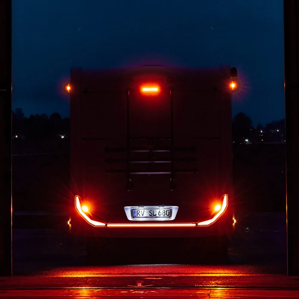 Rückansicht eines beleuchteten Wohnmobils bei Nacht.