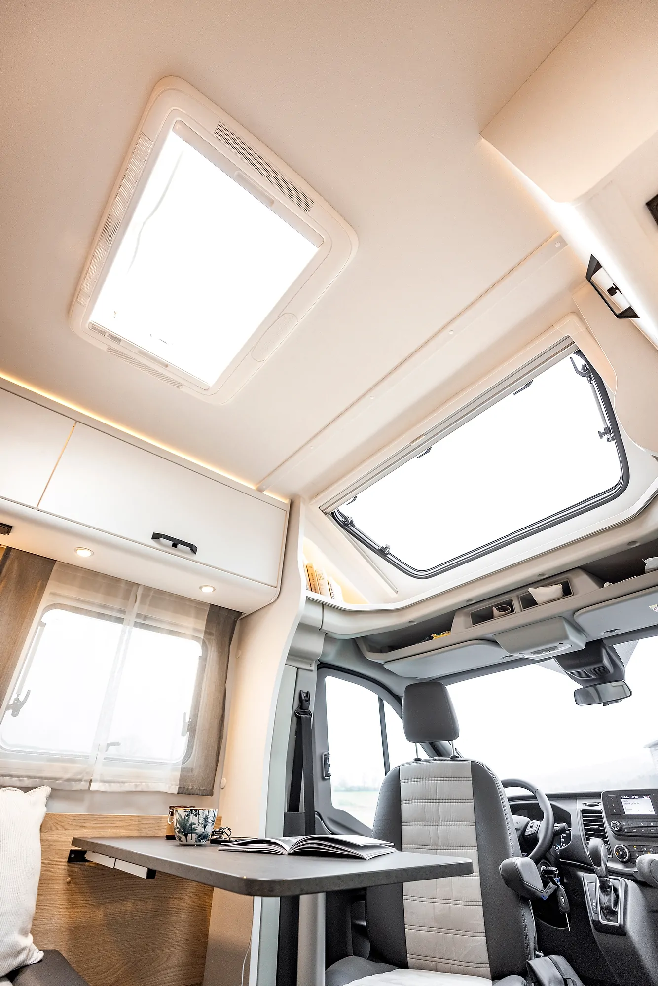 Innenansicht eines teilintegrierten Ford Adventure Wohnmobils mit Tisch und Sitzbereich.