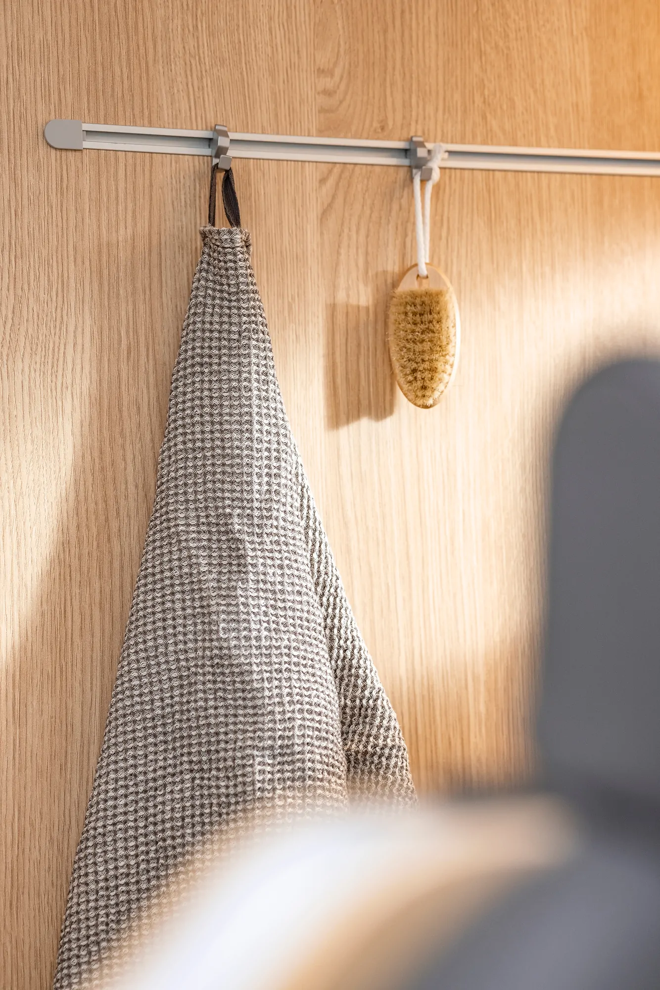 Ein Handtuch und eine Bürste hängen an einer Holzleiste.