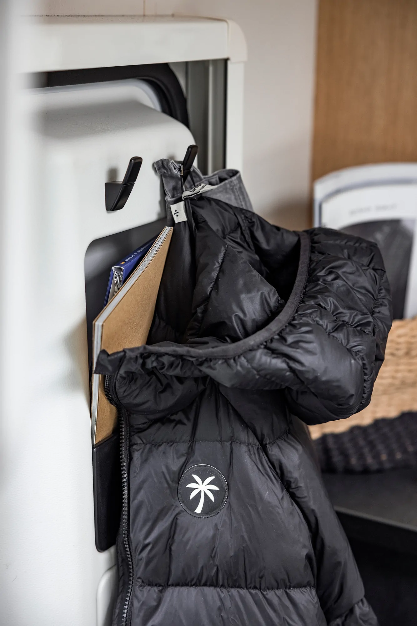 Schwarze Jacke hängt an einem Haken neben einem Ordner.