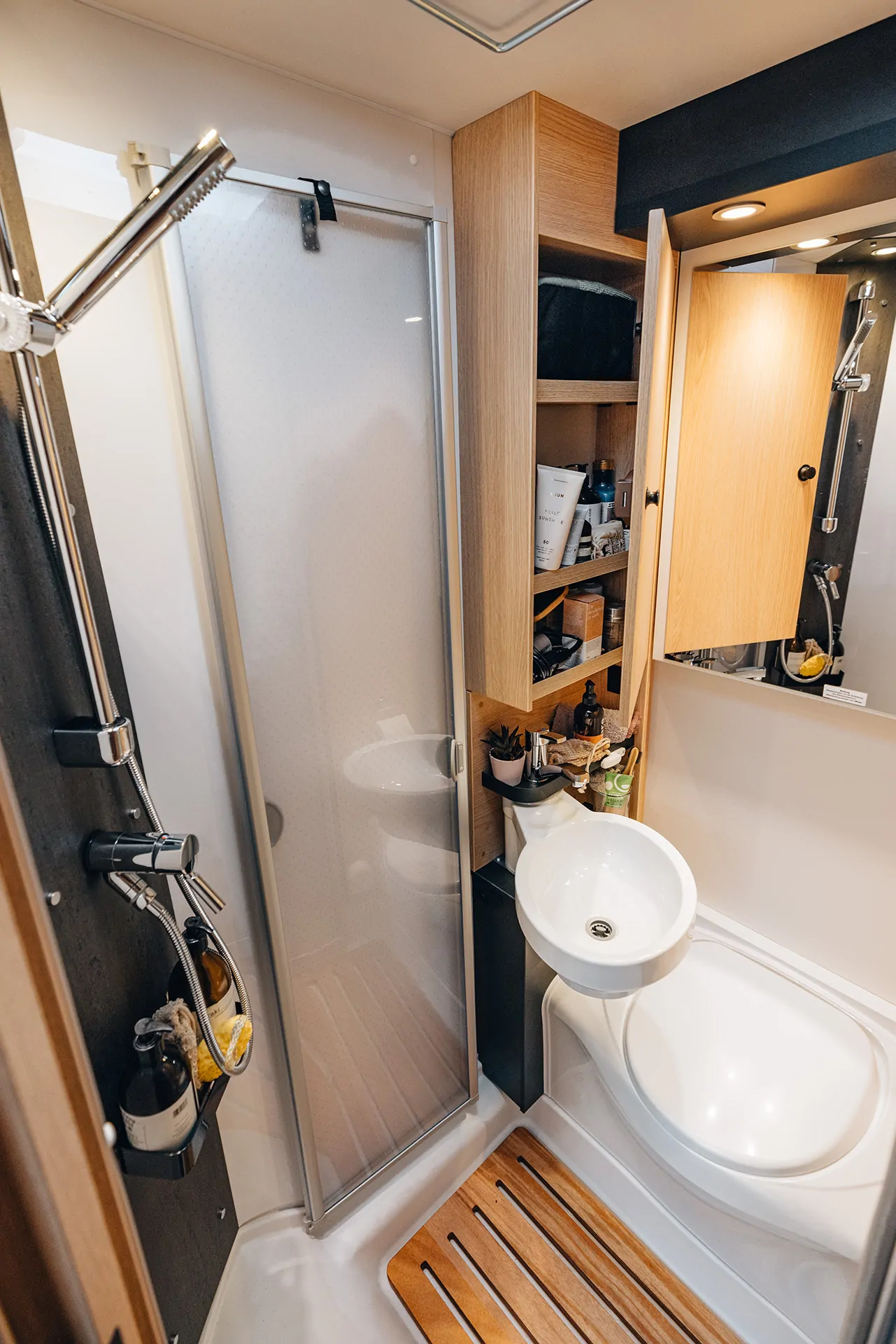 Teilintegrierter Camper-Innenraum mit Dusche, Waschbecken und Stauraum.