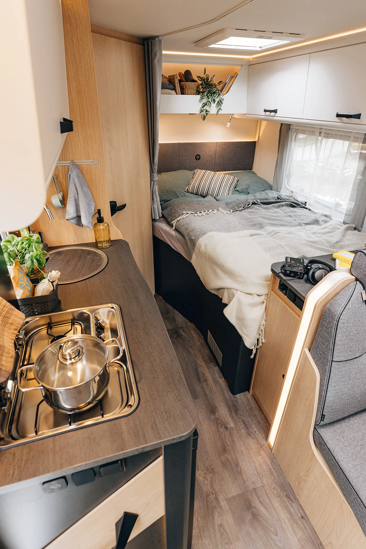 Innenansicht eines teilintegrierten Campers mit Küche und Schlafbereich.