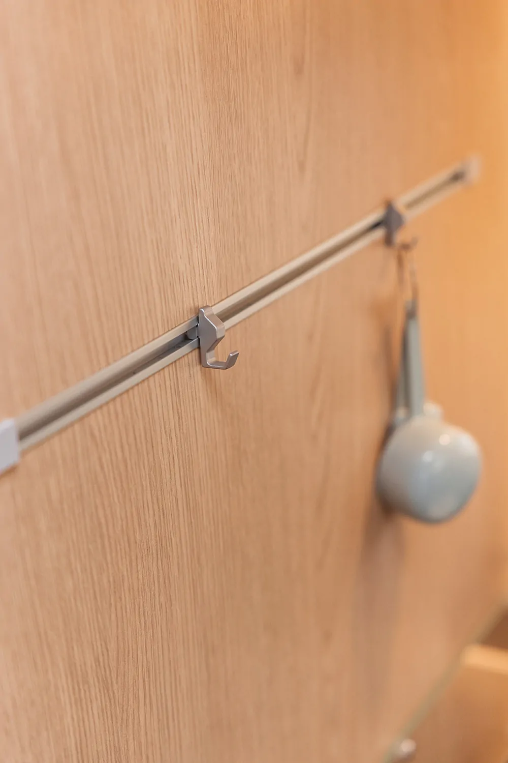 Hakenleiste an einer Holzoberfläche mit einem aufgehängten Becher.