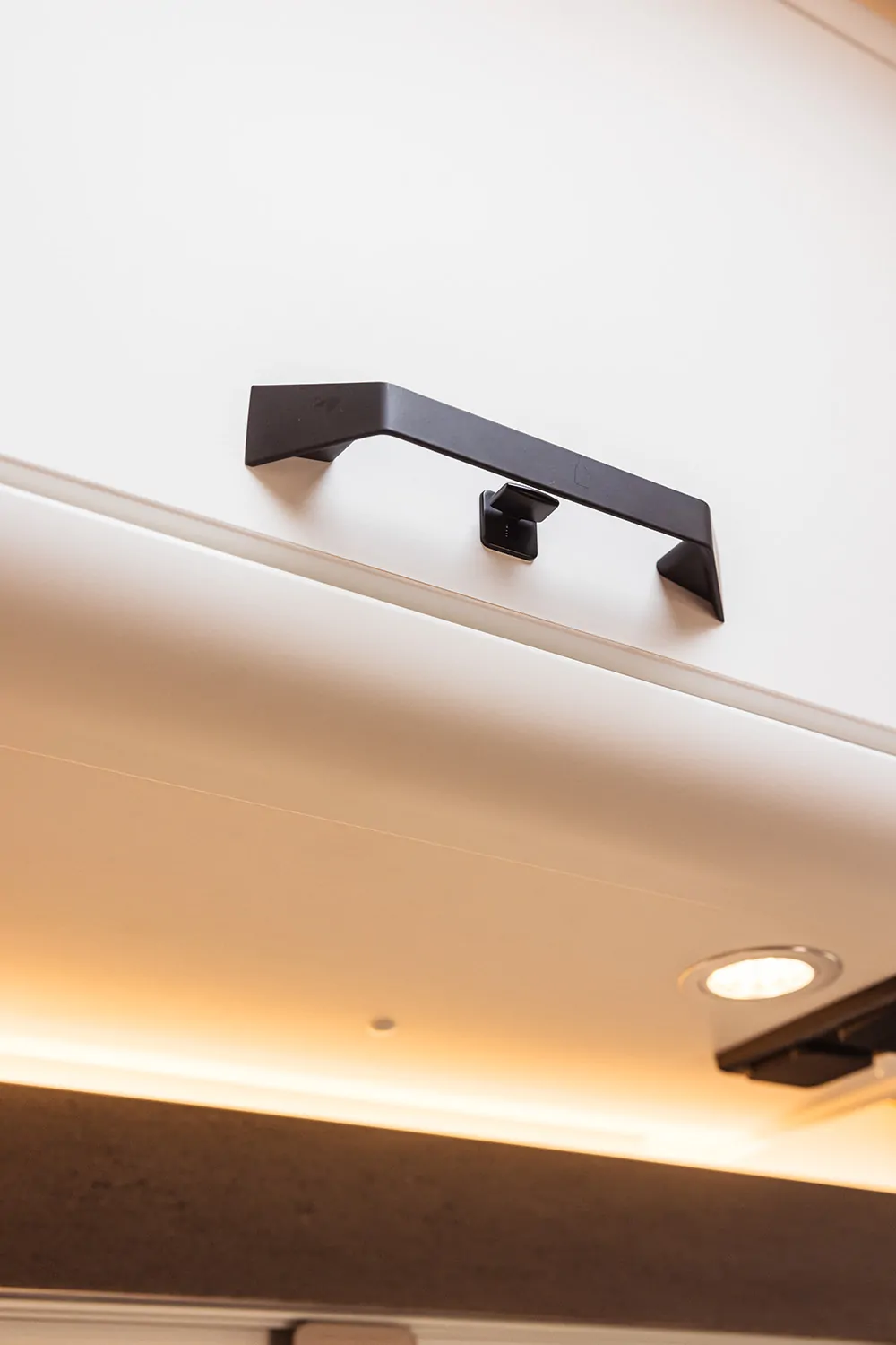 Schwarzer Griff an einem weißen Schrank in einem Wohnmobil.