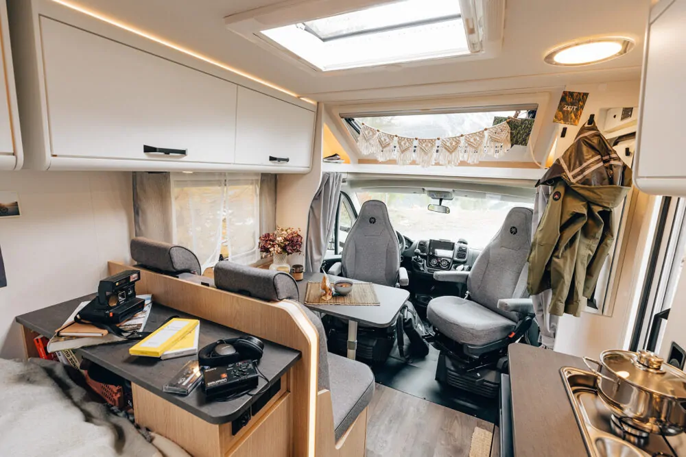 Interieur eines teilintegrierten Wohnmobils mit Sitzgruppe und Küchenzeile.