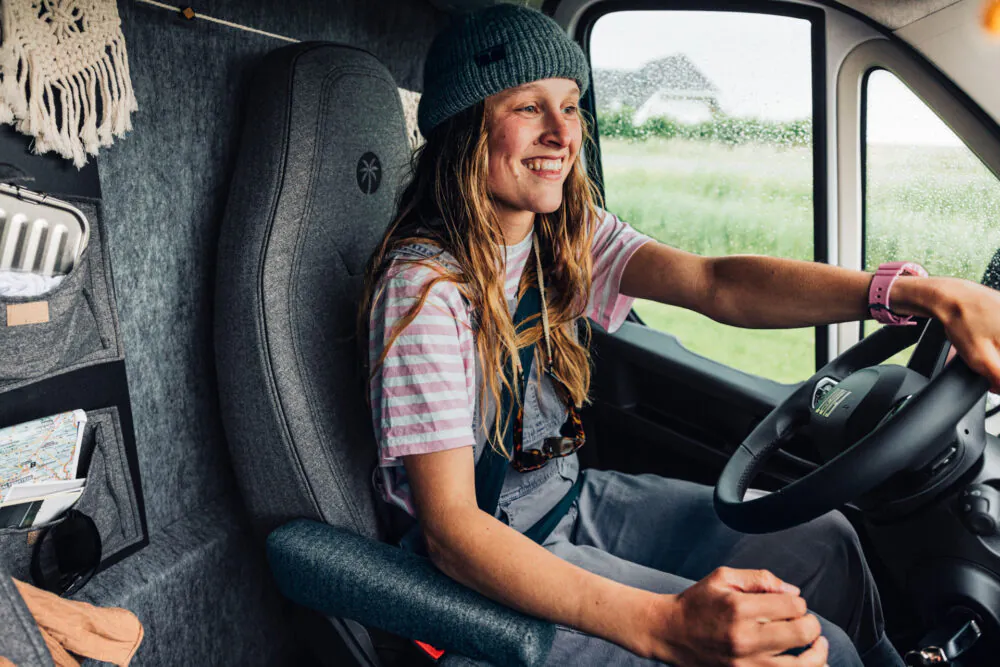 Frau lächelt beim Fahren eines Campers im Regen.
