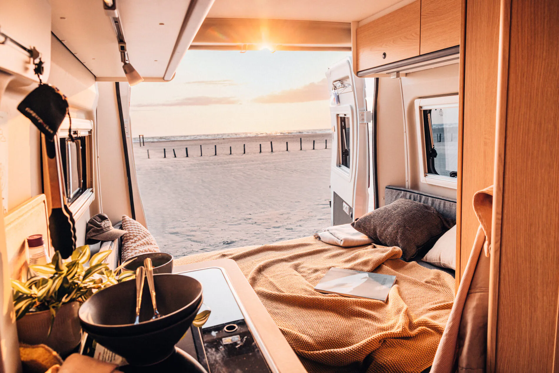 Innenraum eines Campers mit Blick auf den Strand und Sonnenuntergang.