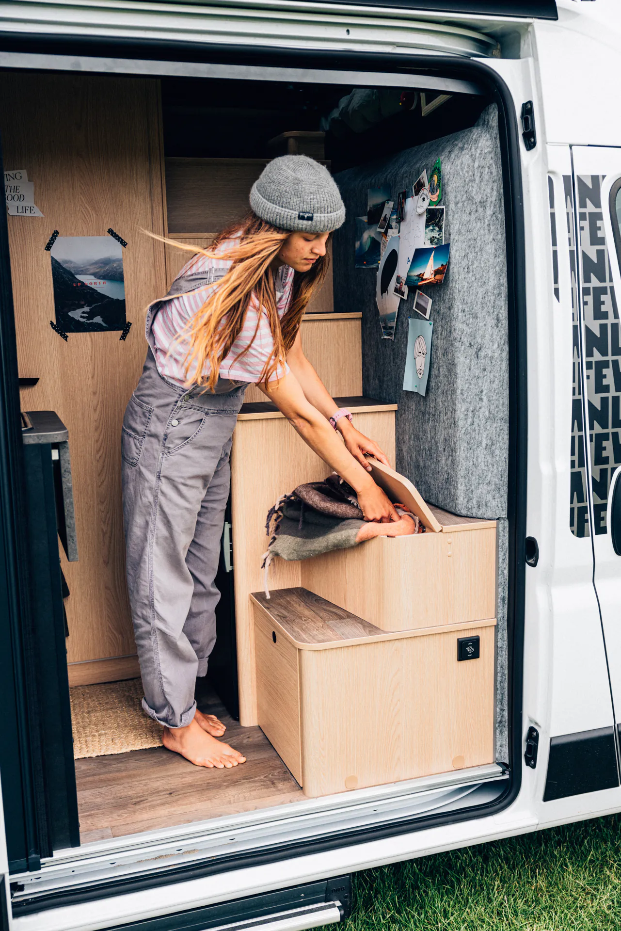 Eine Frau sortiert Decken im Interieur eines Wohnmobils.