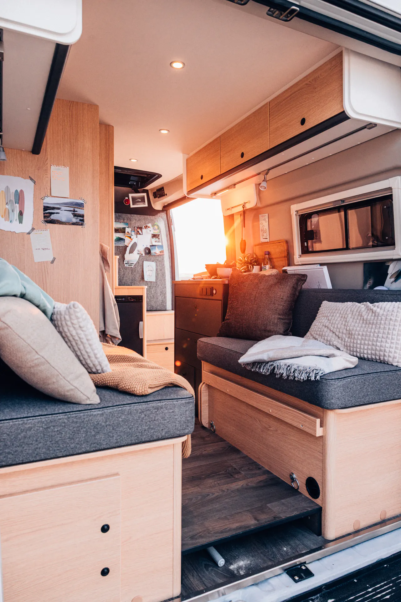 Innenansicht eines gemütlich eingerichteten Campervans mit Sofas und Stauraum.