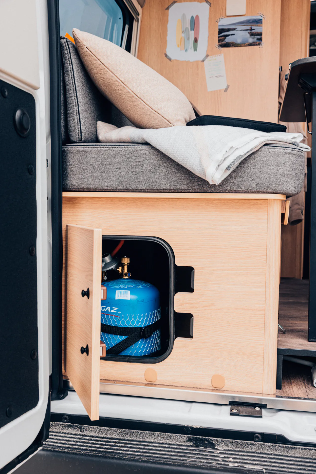 Innenansicht eines Campers mit geöffneter Gasflaschen-Stauraumklappe.