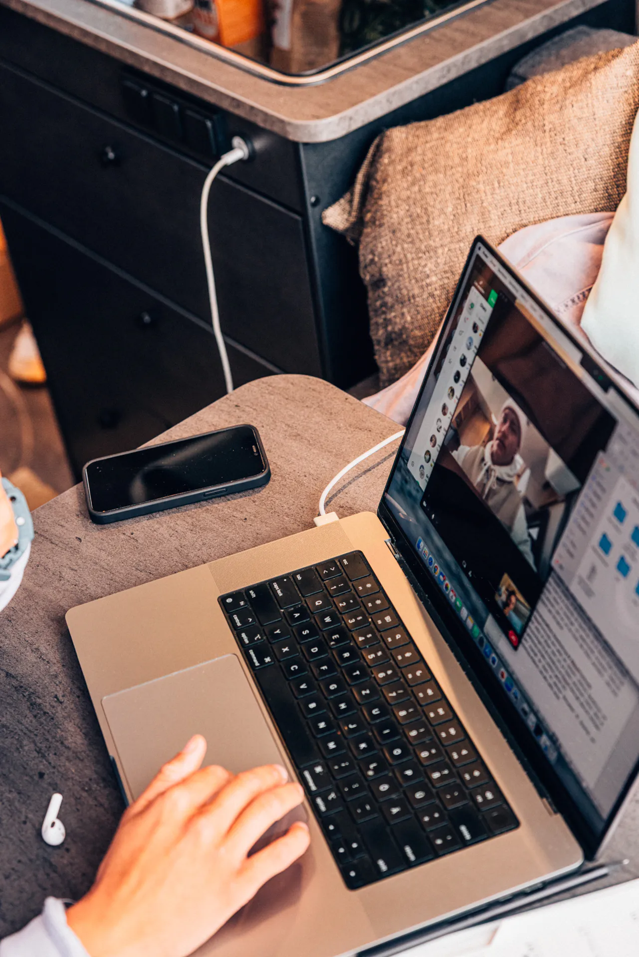 Person arbeitet an einem Laptop in einem Campervan.