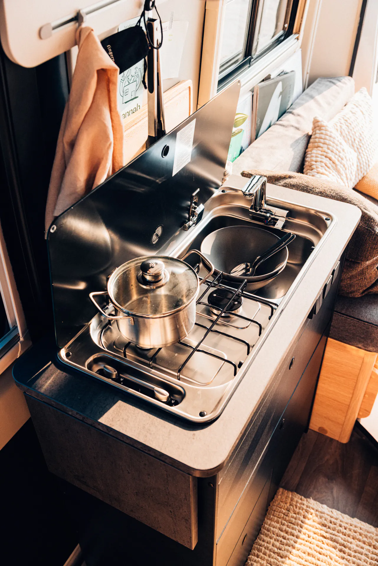 Kompakte Camperküche mit Spüle und Kocher, Topf auf dem Herd.