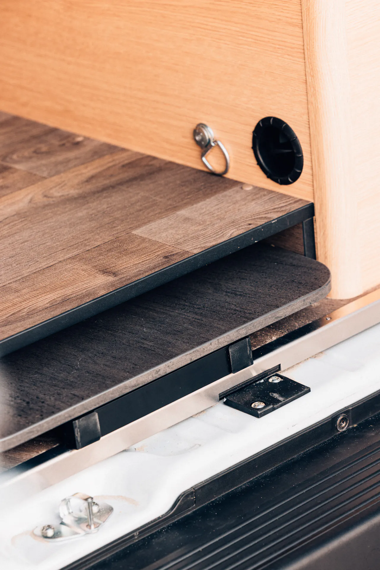 Ein ausziehbares Fach in einem Camper mit Holzverkleidung.