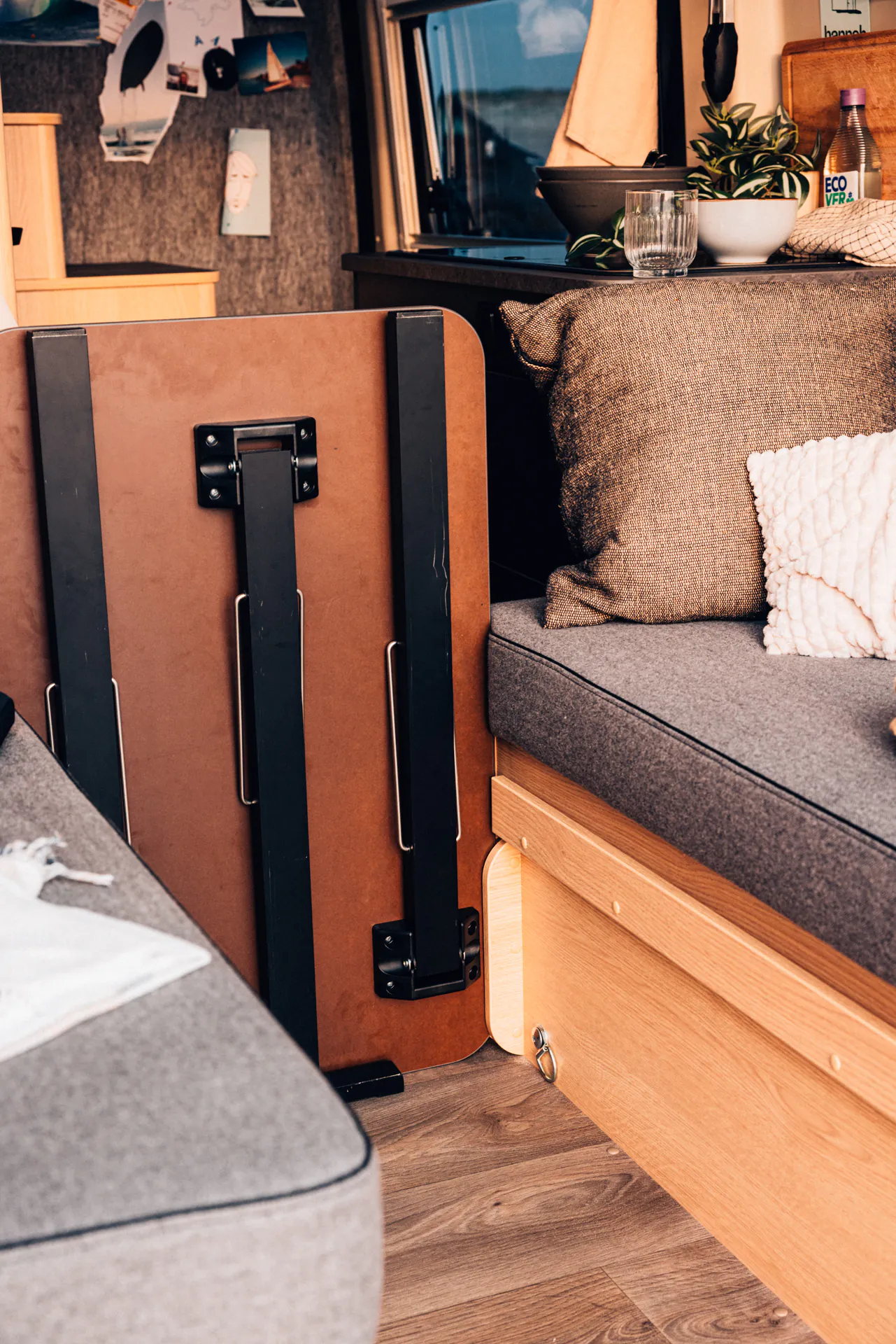 Innenansicht eines gemütlichen Campervans mit Sitzbank, Tisch und Pflanzen.