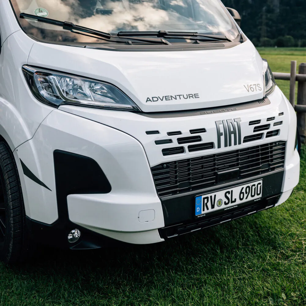 Ein weißer Fiat Adventure V67S Campervan steht auf einer Wiese.