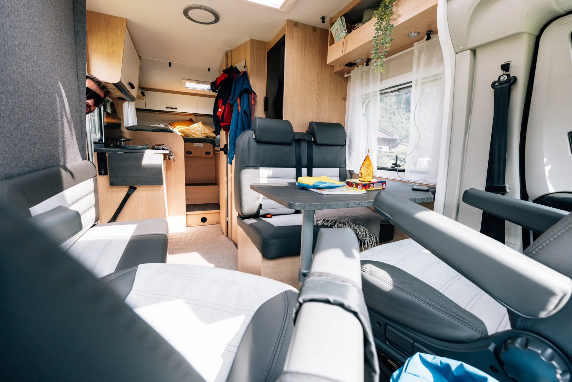 Innenansicht eines Wohnmobils mit Sitzbereich, Tisch und Küche.