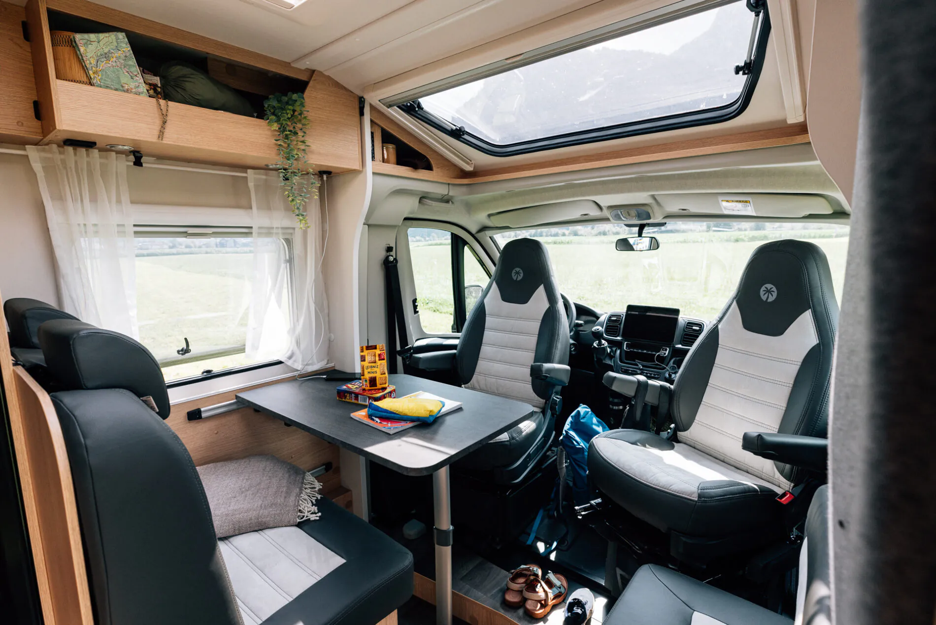 Innenansicht eines Wohnmobils mit Tisch, Sitzen und Oberlicht.