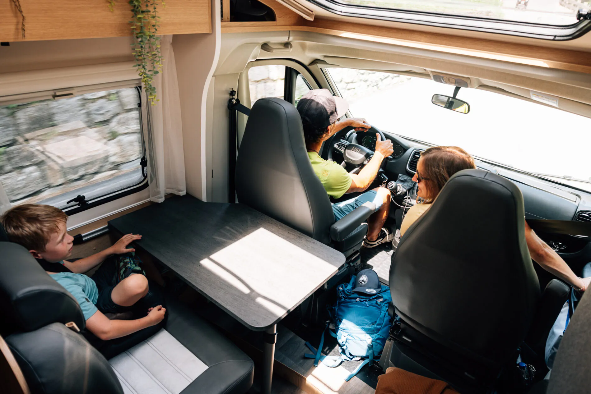 Innenansicht eines fahrenden Fiat-Campers mit drei Personen.