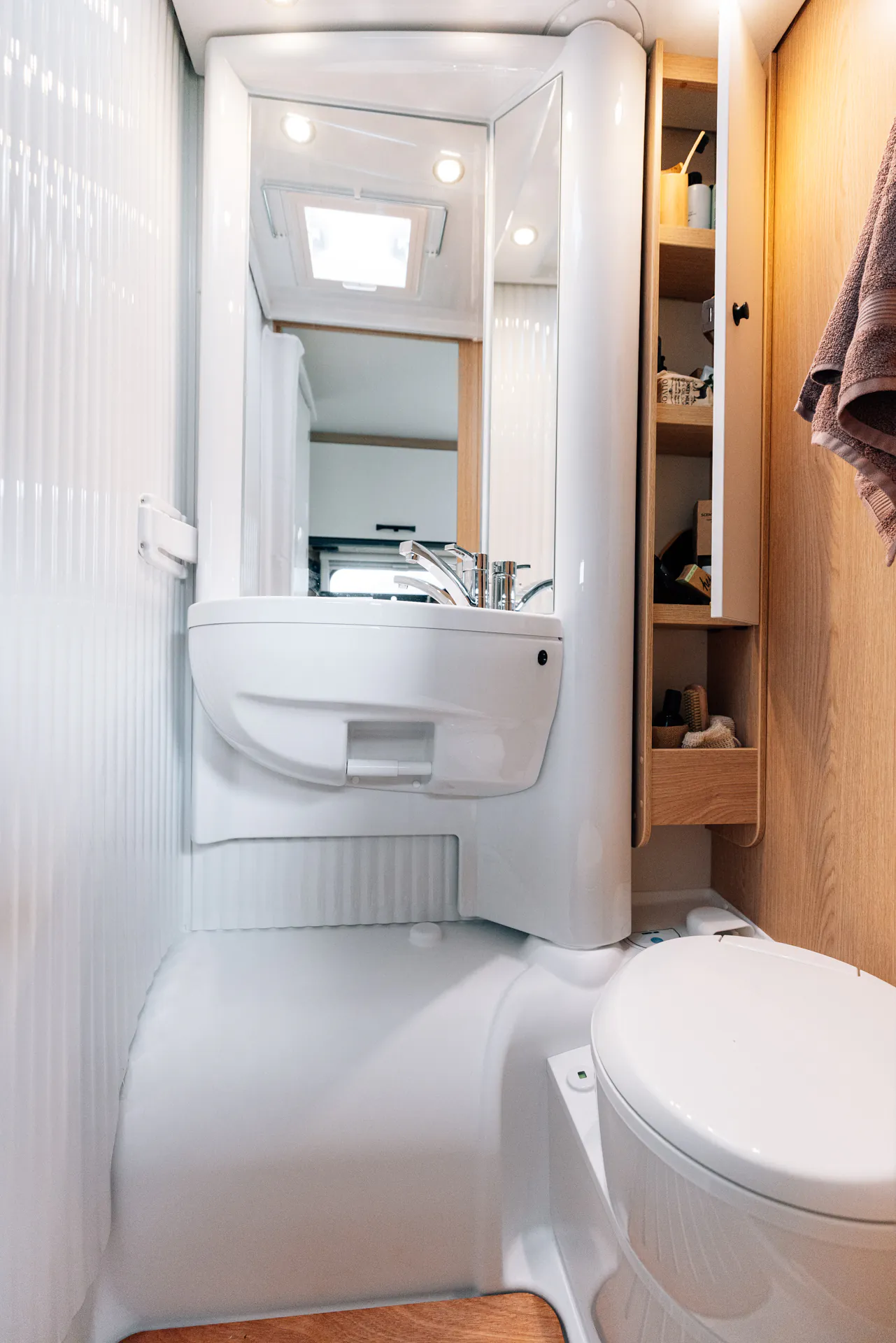 Kompaktes Badezimmer im Wohnmobil mit Waschbecken und Toilette.