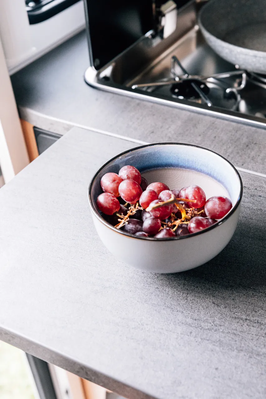 Schale mit roten und schwarzen Trauben auf einer Küchenarbeitsplatte.