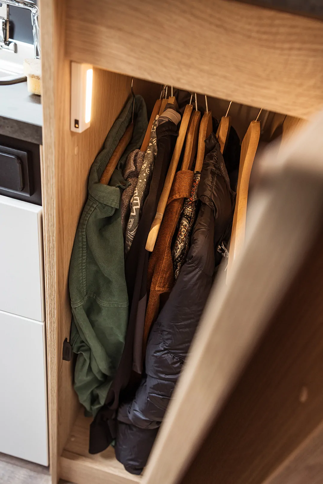 Kleiderschrank mit mehreren Jacken auf Holzkleiderbügeln.