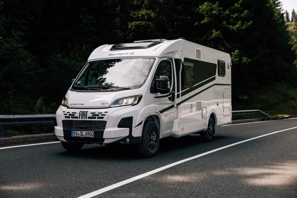 Ein weißes Fiat Sunlight V67S Wohnmobil fährt auf einer Landstraße.