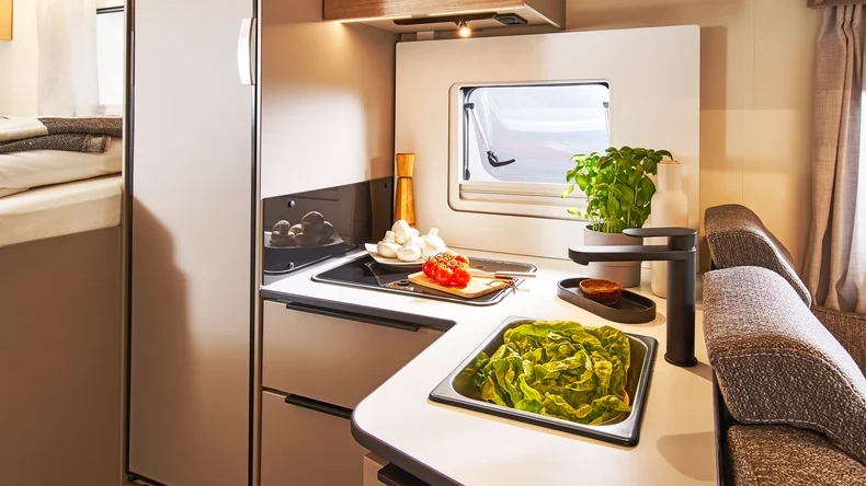 Eine moderne Wohnmobilküche im Bürstner Campeo TD 690 mit frischem Gemüse auf der Arbeitsfläche.