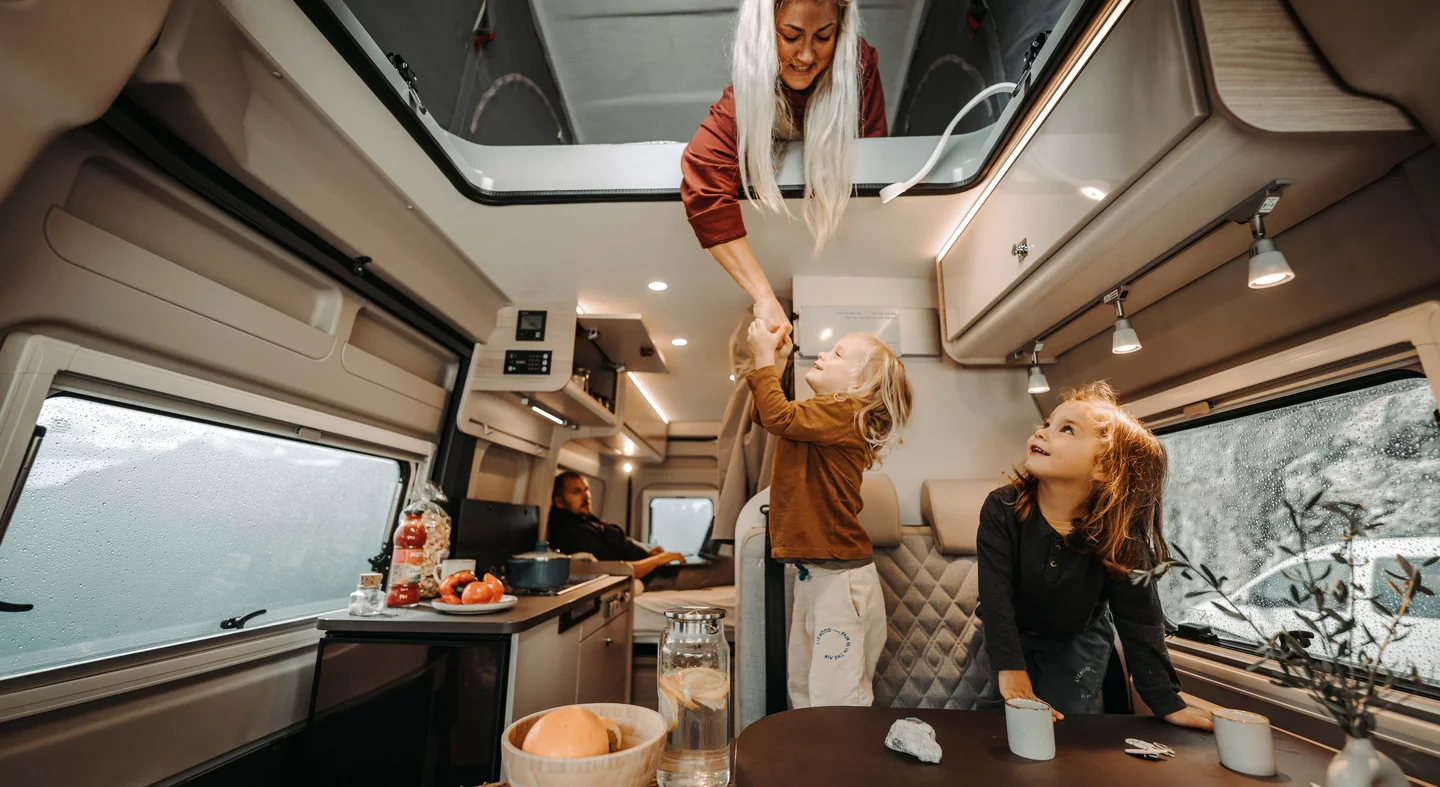 Familie interagiert fröhlich im Inneren eines Wohnmobils.