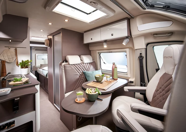 Innenansicht eines modernen Wohnmobils mit Essbereich und Küche.